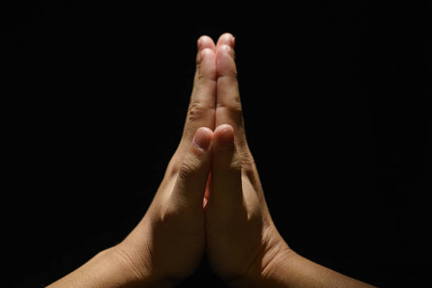 Praying for faith in religion. Belief in God on dark background. Clasped hands. Power of hope, love and devotion. Namaste gesture. Prayer position. Cropped shot of an unrecognizable person with hands together. Concept of trust to Christianity. Appeal to heaven, request for donate or forgiveness