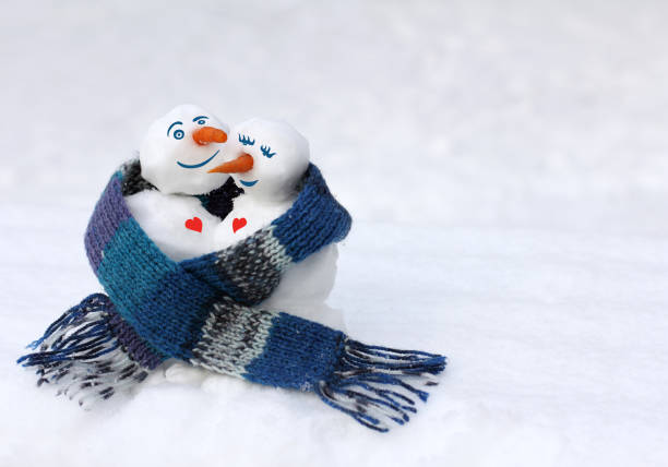 pair of snowmen together covered with a large knitted scarf
