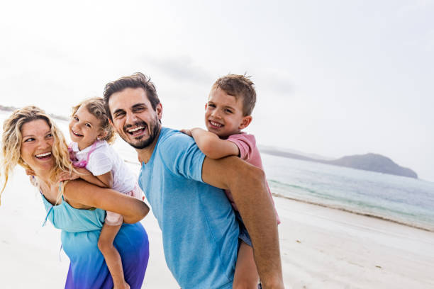 istock Playful family having fun while piggybacking on the beach. 1202216385