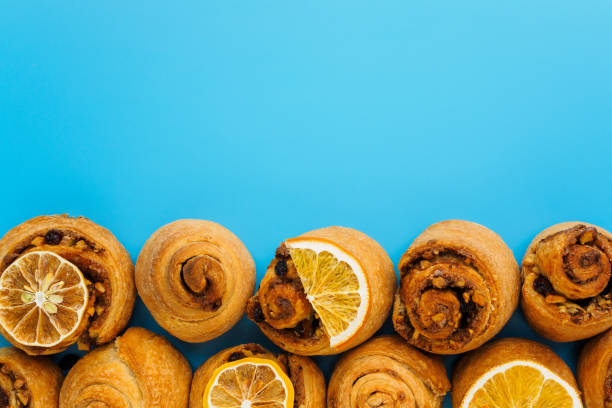 istock Buns with cinnamon, nuts and raisins and lemon slices on a blue background with copy space 1202218827