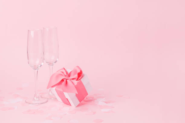 istock White gift box and wine glasses on pink background, decorated bow, creating romantic luxury atmosphere. For birthday, anniversary, wedding, woman day, valentine presents, gift post card 1202219007