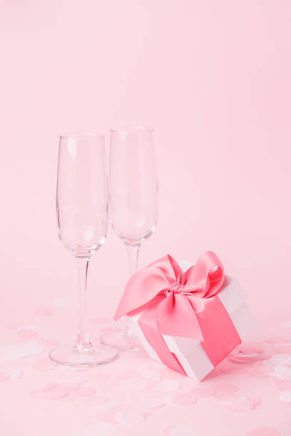 istock White gift box and wine glasses on pink background, decorated bow, creating romantic luxury atmosphere. For birthday, anniversary, wedding, woman day, valentine presents, gift post card 1202219021