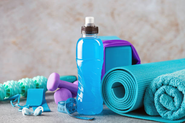 Drink isotonic bottle and fitness equipment on a grey background. Sport, fitness or yoga concept Drink isotonic bottle and fitness equipment on a grey background. Sport, fitness or yoga concept sport drink stock pictures, royalty-free photos & images