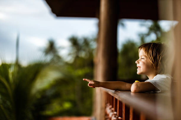Cute little boy relaxing on a balcony and aiming at something. Copy space.