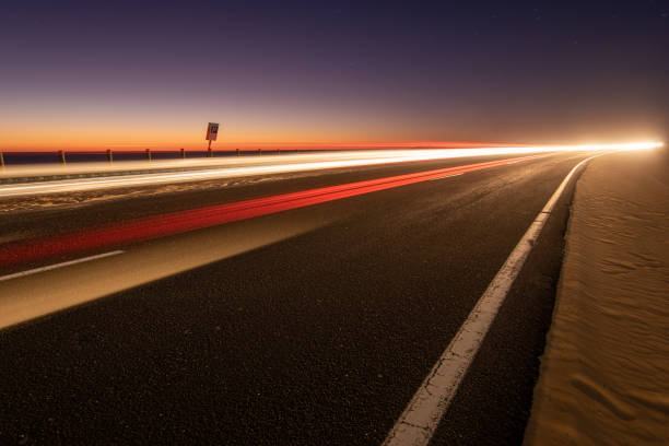 istock asphalt road running through the sandy desert at night 1202223680