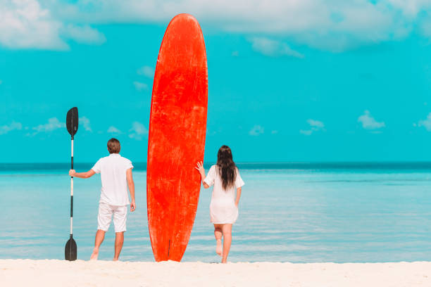istock Young couple with red surfboard during tropical vacation 1202225454