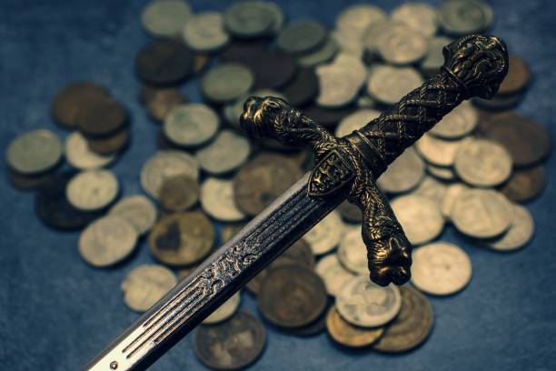 istock Knight's sword on coins background 1202225516