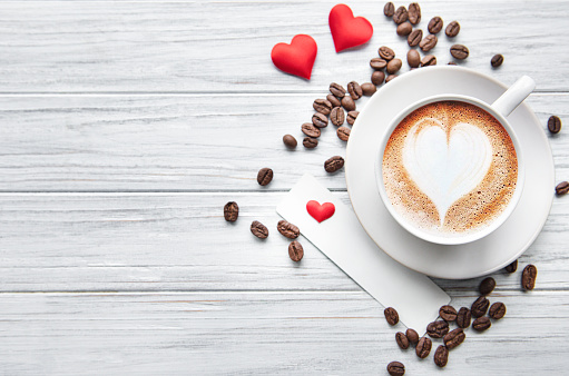 A cup of coffee with heart pattern  on a white wooden background