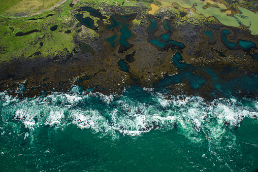 Aerial view of turquoise-colored sea coastline of Iceland.