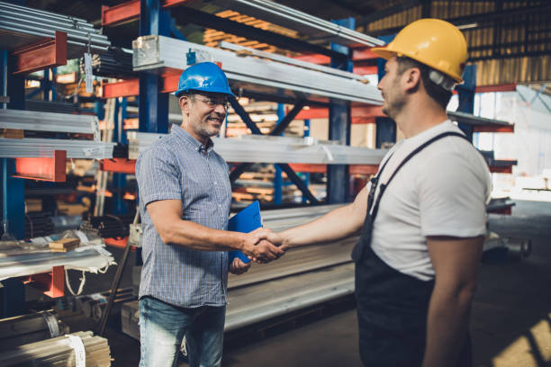 istock Smiling metal worker greeting manager in aluminum mill. 1202229293
