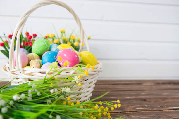 istock Colored easter eggs in the basket and spring flowers on wooden background. Greeting card 1202231702
