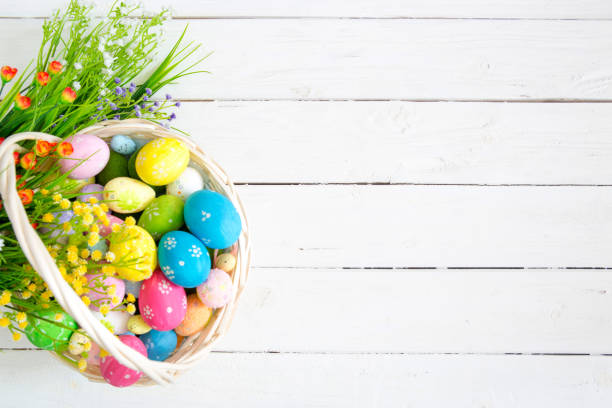 uova di pasqua colorate in cesto e fiori su tavolo di legno bianco. visualizzazione dall'alto con spazio di copia - wood eggs easter easter egg foto e immagini stock