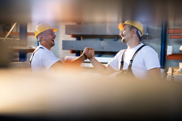 istock Happy manual workers greeting each other in aluminum mill. 1202233077