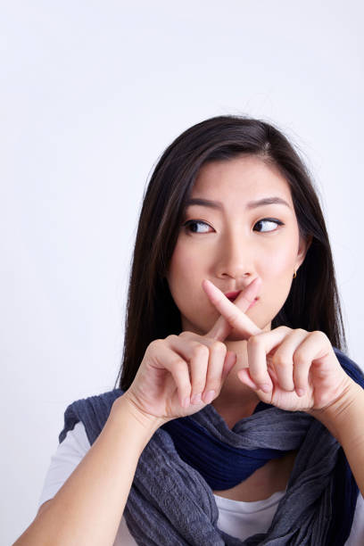 istock women with hand sign quiet 1202233260