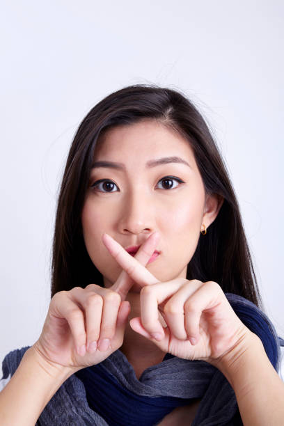 istock women with hand sign quiet 1202233301