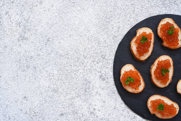 toast bread with red caviar. sandwich with caviar and butter on a concrete background. - plank bread caviar close up imagens e fotografias de stock