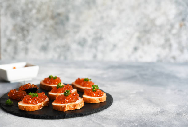 toast bread with red caviar. sandwich with caviar and butter on a concrete background. - plank bread caviar close up imagens e fotografias de stock