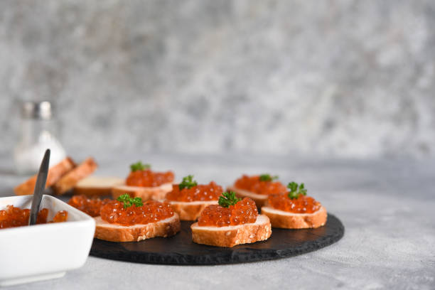 toast bread with red caviar. sandwich with caviar and butter on a concrete background. - plank bread caviar close up imagens e fotografias de stock