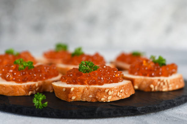 toast bread with red caviar. sandwich with caviar and butter on a concrete background. - plank bread caviar close up imagens e fotografias de stock