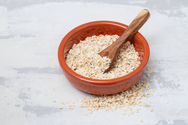 istock dry oats with spoon in brown ceramic bowl on ceramic background 1202234924