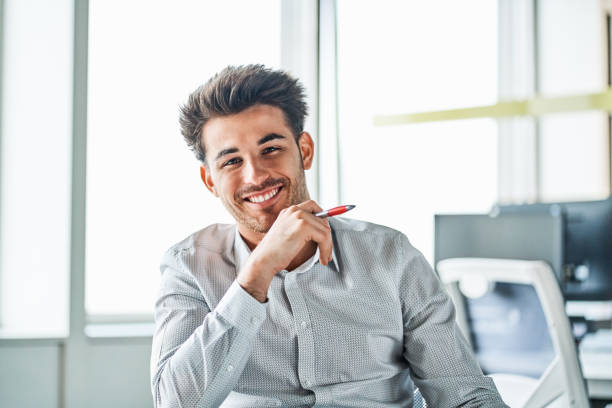 istock Smiling young businessman sitting in office 1202235526
