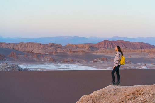 Young Caucasian woman walking in Atacama desert in Chile  at sunset, Salar de Atacama, Valle de la Luna
