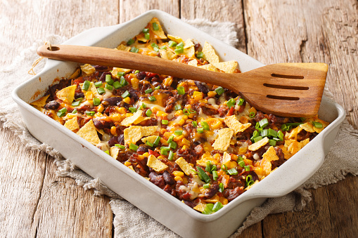 Crispy homemade frito pie with beef, cheese, corn, beans and chips close-up in a baking dish on the table. horizontal