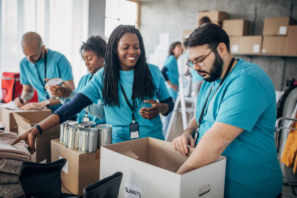 Diverse volunteers packing donation boxes in charity food bank Multi-ethnic group of people, diverse volunteers packing donation boxes in charity food bank. food bank stock pictures, royalty-free photos & images