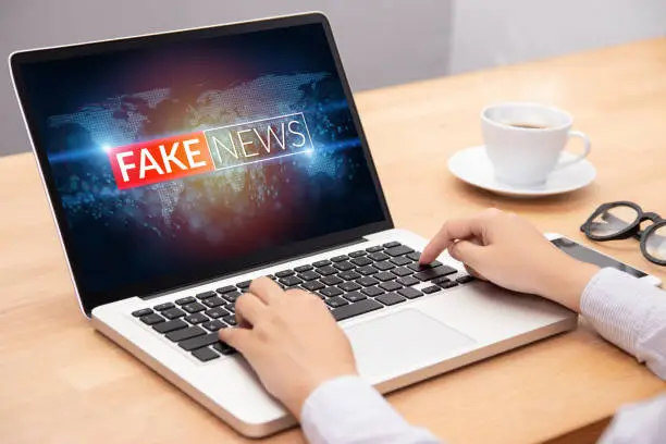 Photo of people reading fake news or HOAX on internet content via laptop