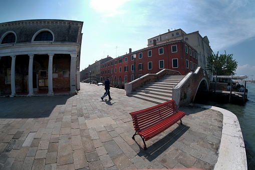 La Giudecca  Island-Venezia- Italy-April 26, 2018: VENEZIA- La Giudecca Island - Fondamenta Sant'Eufemia- An empty bench and a pedestrian bridge. views of the Venetian island.