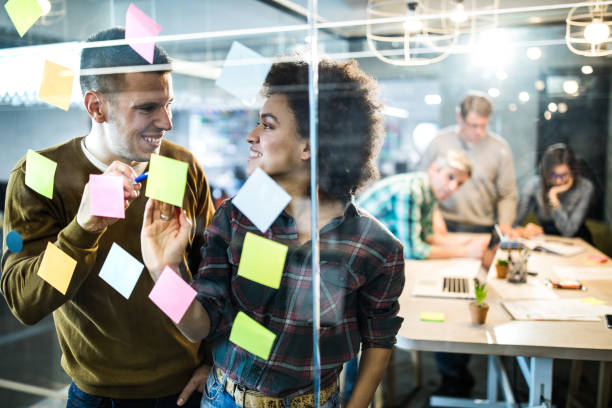 istock Happy creative people talking while making mind map on a glass wall in the office. 1202238268