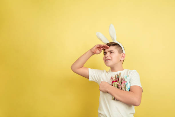 istock Easter bunny boy with bright emotions on yellow studio background 1202241360
