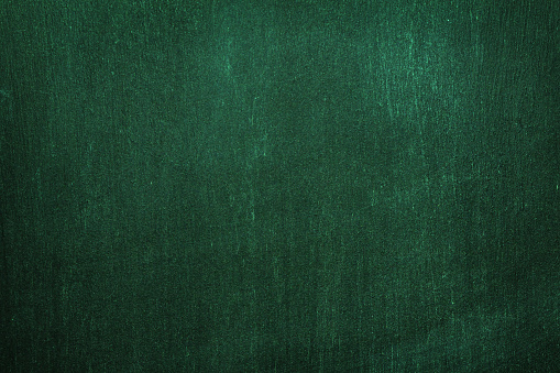 Dark green wall texture for a designer background. Artistic plaster of a rough wooden surface with dark night lighting
