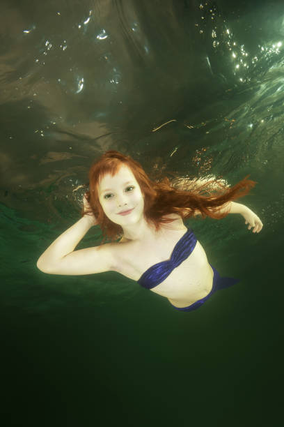 istock Young red-haired mermaid swims underwater 1202244048
