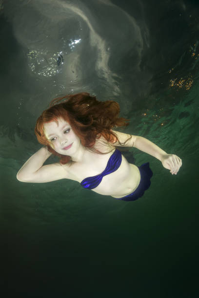 istock Young red-haired mermaid swims underwater 1202244058
