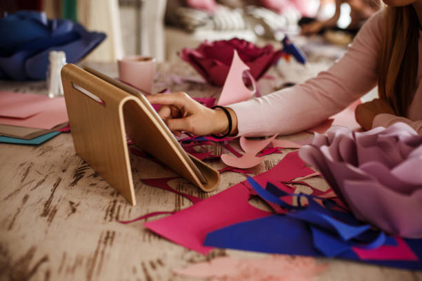 istock Woman following tutorial on digital tablet on DIY paper flowers she is making 1202246587