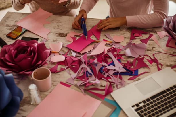 istock Two unrecognizable young women making paper flowers together as a team 1202246593