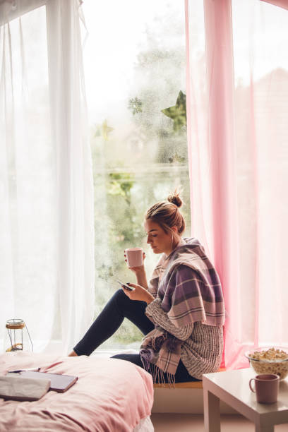 istock Young woman relaxing on the weekend on her window sill 1202247124