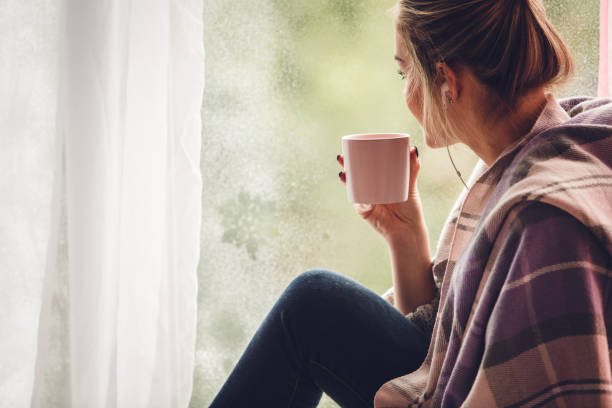 młoda kobieta popijając kawę, słuchając muzyki i relaksując się na parapecie - window sill audio zdjęcia i obrazy z banku zdjęć