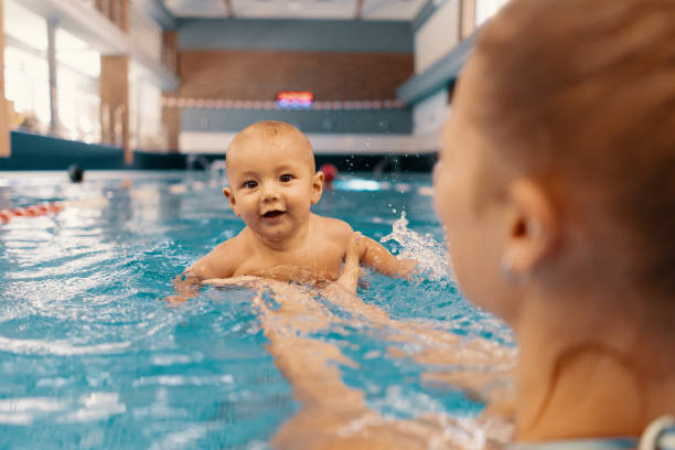 istock Mother and little son having fun in a swimming pool 1202247304