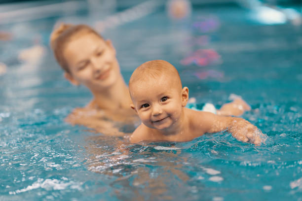istock Mother and little son having fun in a swimming pool 1202247309