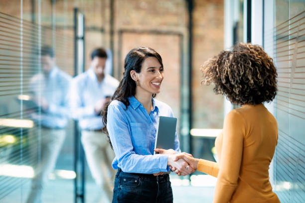 Opportunity comes to those who go to it Two Businesswomen Shaking Hands In Modern Office. Successful businesswomen are shaking hands. They are standing near the office and smiling. They made a deal casual handshake stock pictures, royalty-free photos & images