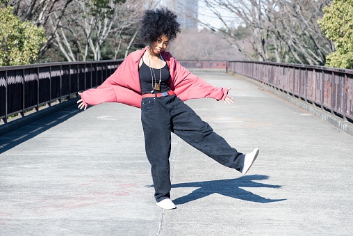 A young woman practicing her dance moves outside on a sunny winter day.