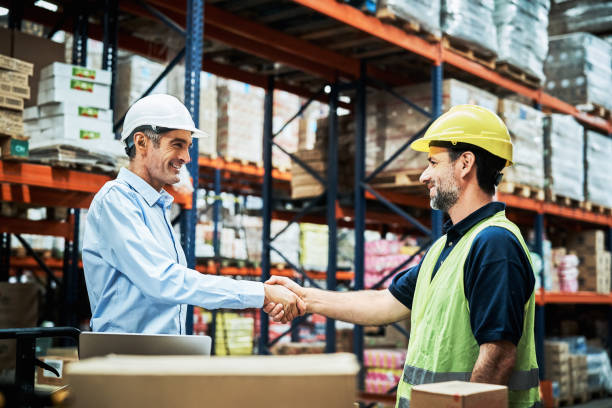 istock Happy manager shaking hands with worker at factory 1202255378