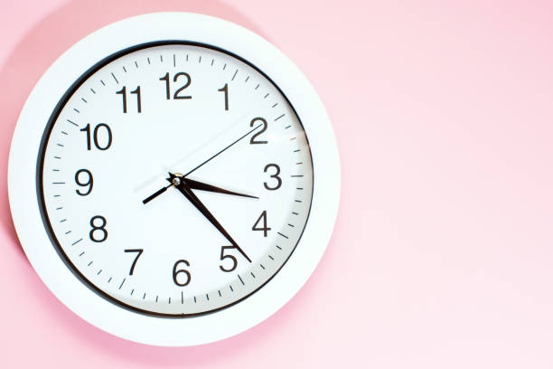 istock Part of a white wall clock. Close-up image of a plastic wall clock on a pink background with a copy of the space. 1202255607
