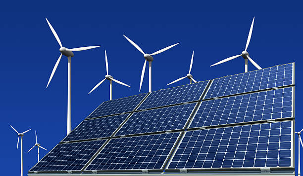 Monocrystalline solar modules and wind turbines against a blue background stock photo