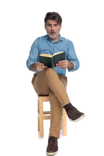 istock Amazed casual man reading a book and gasping 1202257155