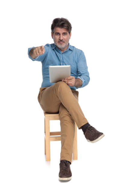 istock Positive casual man holding a tablet and pointing forward 1202257304