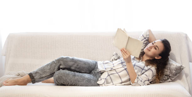 istock Woman reading a book on the couch. 1202257909
