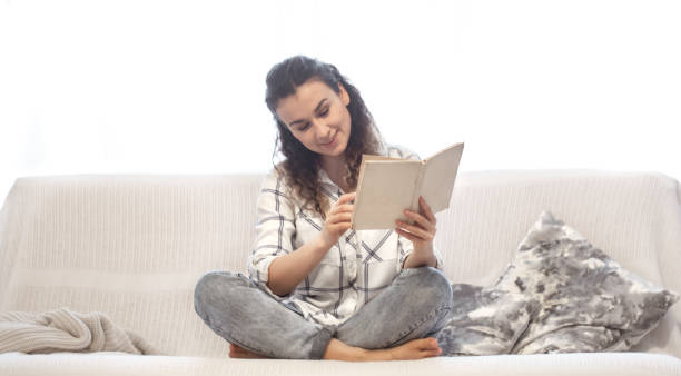 istock Woman reading a book on the couch. 1202257922